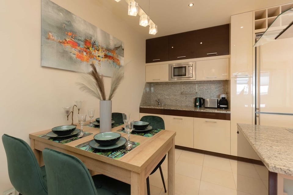A dining table with green chairs, a decorative vase, and stylish table settings.
