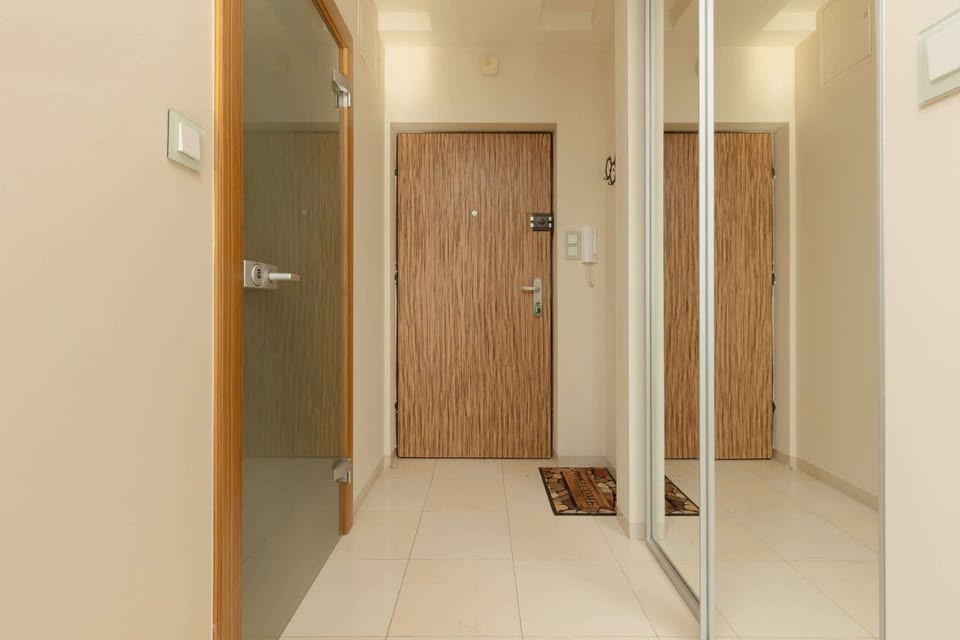 An entryway featuring a wooden door, a mirror, and a neat storage area.
