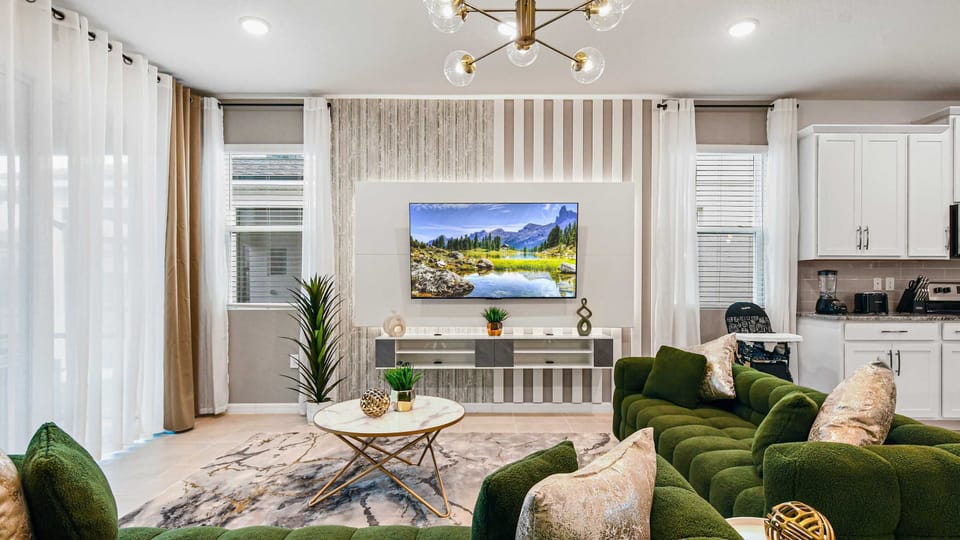 Chic modern living room with plush green seating and sleek kitchen access nearby.