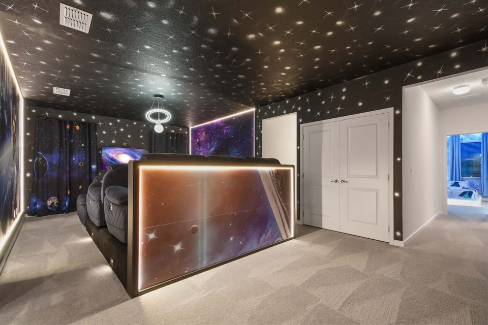 Immersive galaxy-themed theater room with starry ceiling and plush recliners
