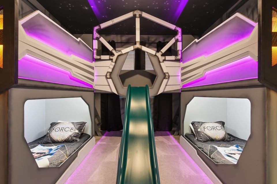 Galactic-themed kids' room with slide, twin beds, and glowing space vibes
