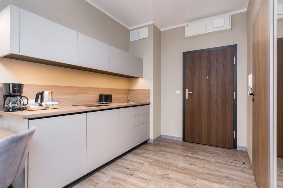 A sleek kitchen with built-in appliances, white cabinets, and a wooden countertop.
