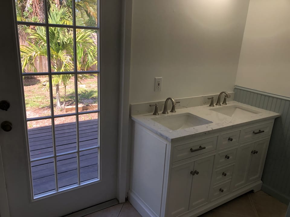 Primary bath double vanity with door leading to private deck