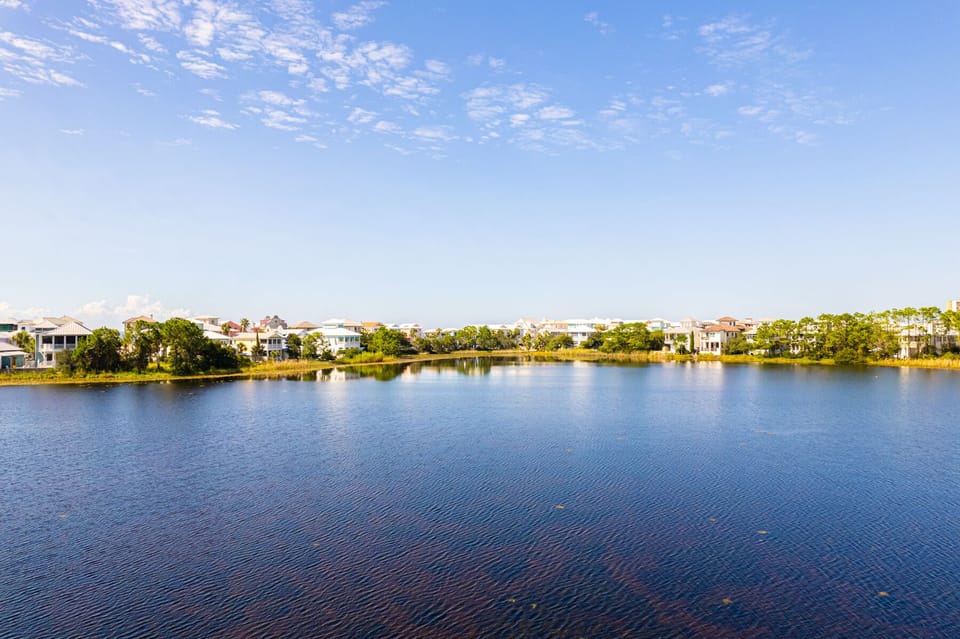 Serene lakefront community with beautiful homes nestled among lush trees under a picturesque sky.