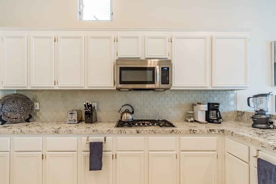 Stainless steel stove top and microwave. Pots and pans located underneath