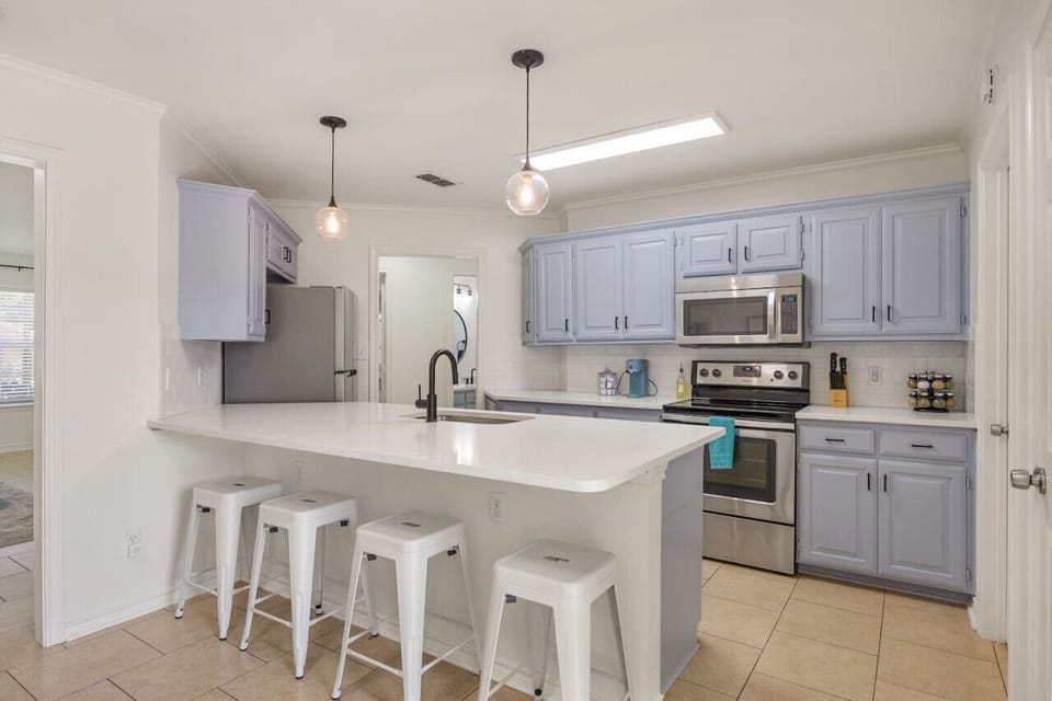 This cheerful kitchen is designed to bring everyone together. Bright cabinets and modern lighting set the tone, while stainless steel appliances make cooking a breeze. The kitchen comes fully stocked with cookware, dishes, utensils, and all the essentials