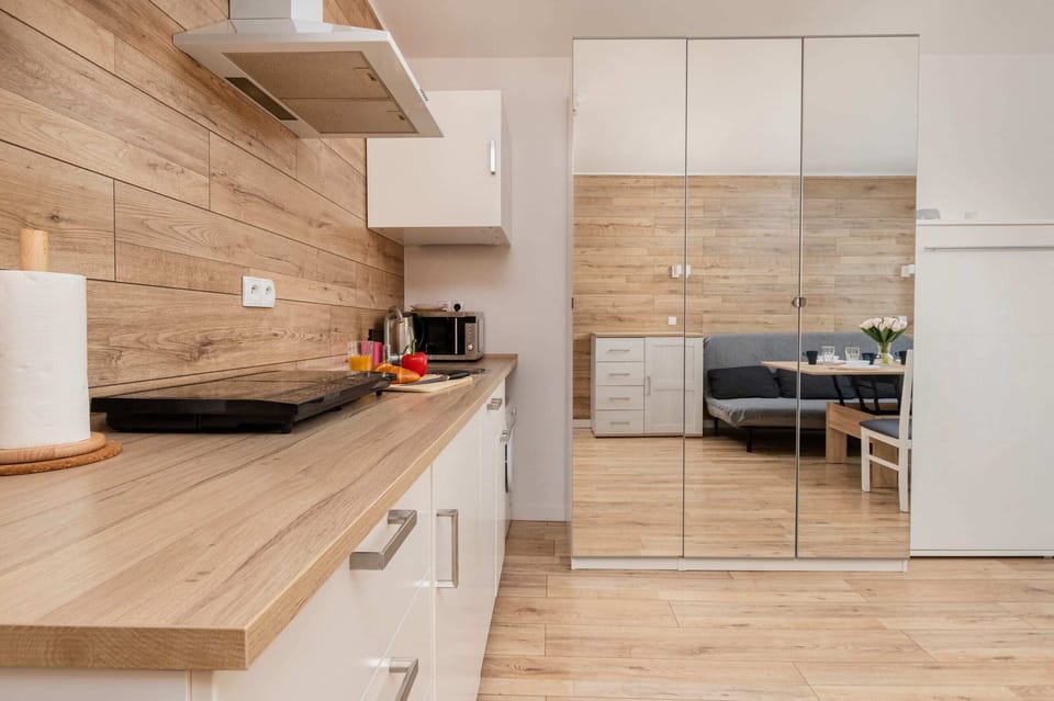 A sleek kitchen with white cabinets, modern appliances, and a wooden countertop.
