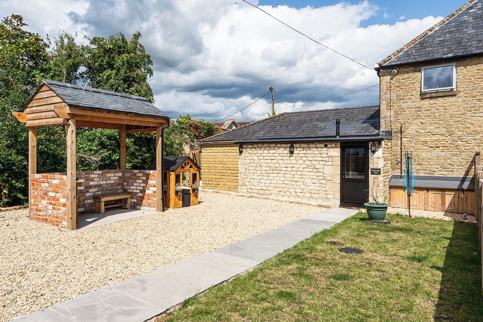 Communal garden with BBQ area, and path leading to pool and spa facilities.