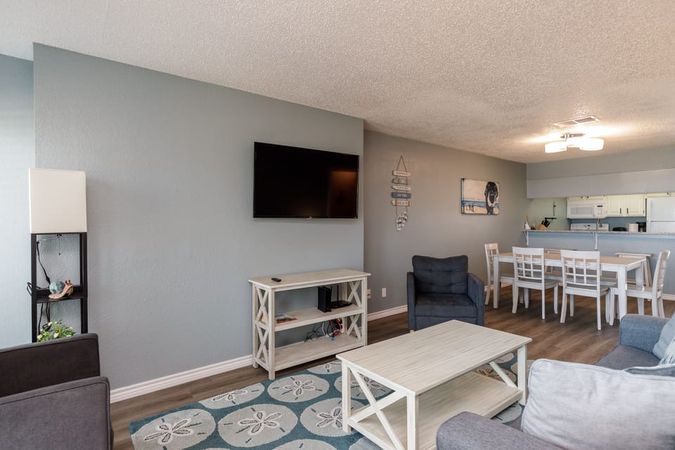 Unwind in your spacious living room featuring a large smart TV, cozy seating, and open-concept design flowing to the dining area.