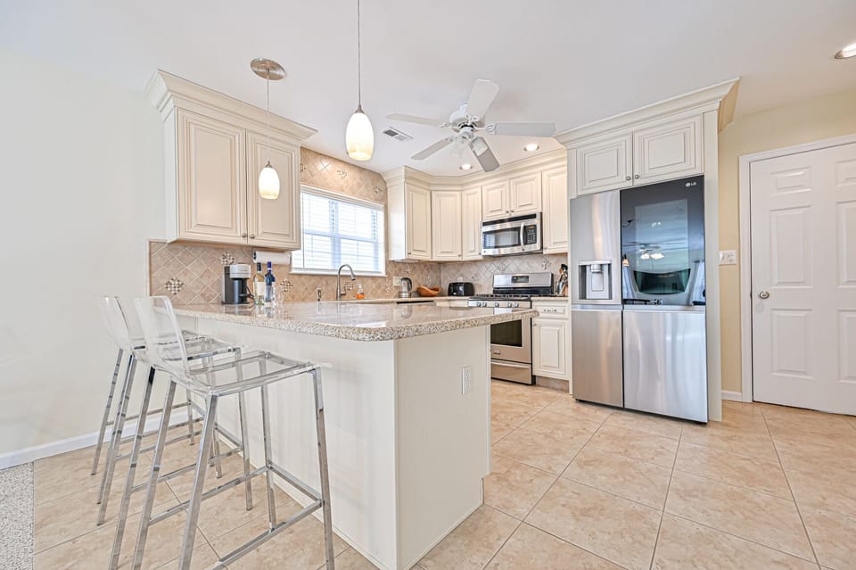 Kitchen with additional counter seating, Nespresso machine, & drip coffee maker.