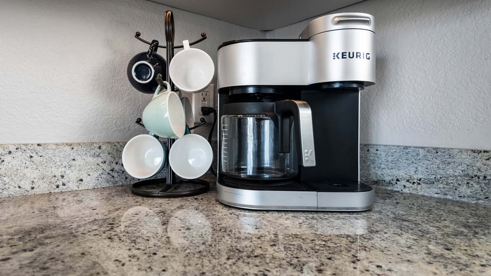 Coffee station with Keurig coffee maker, mug rack, and convenient countertop setup for enjoying morning coffee during your Galveston getaway.