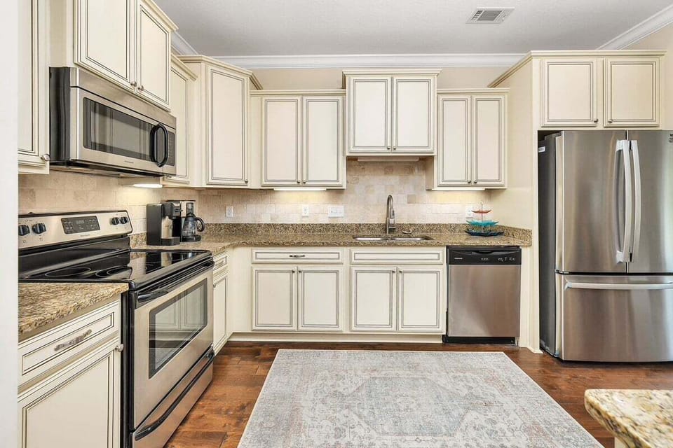 Kitchen with cream cabinets, granite counters, and stainless appliances