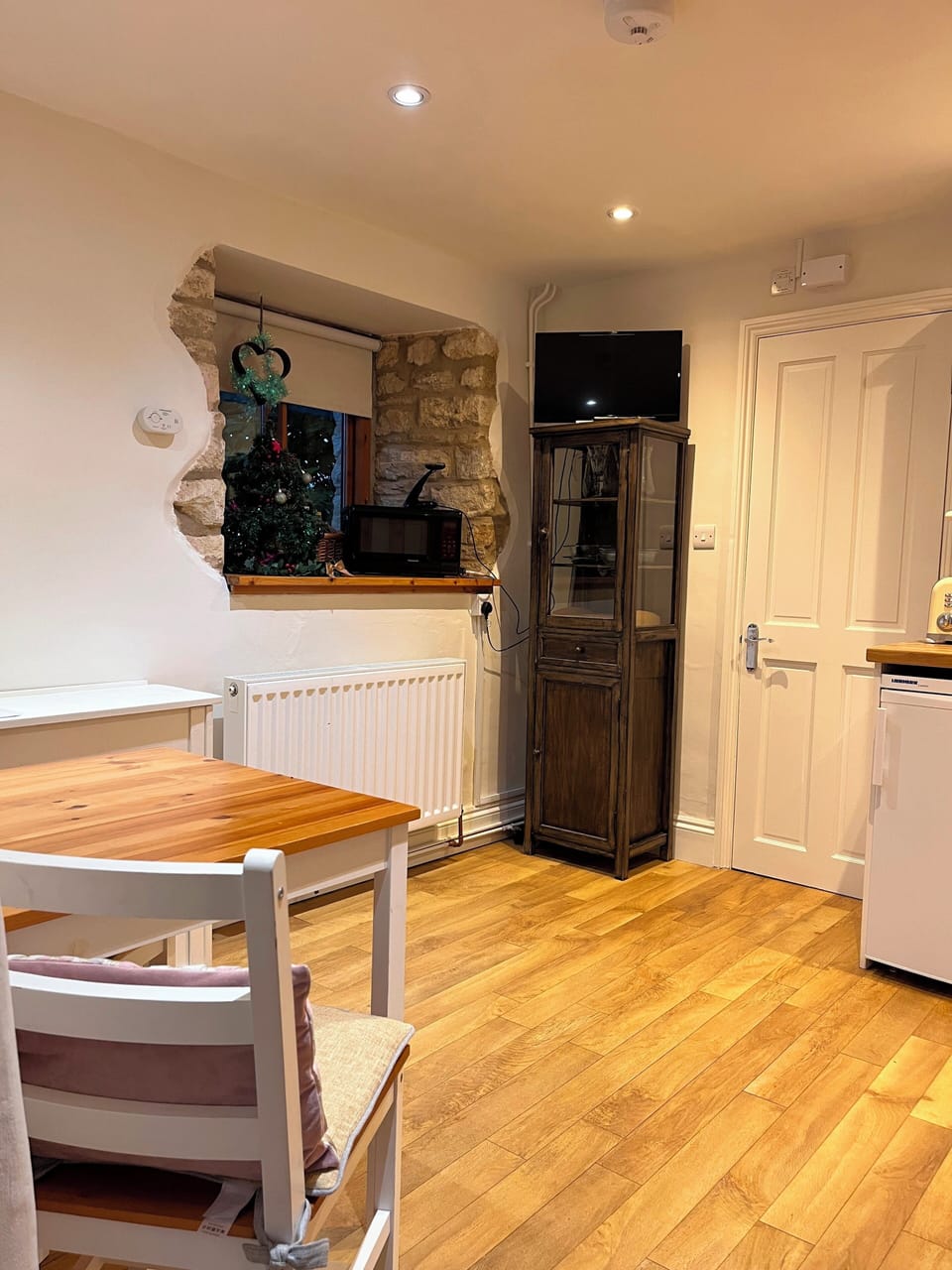 Open plan downstairs space with a TV, seating, dining table and kitchen.
