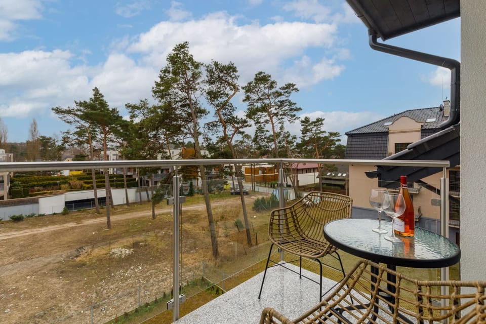 A balcony with a table and chairs, overlooking a peaceful residential area and greenery.
