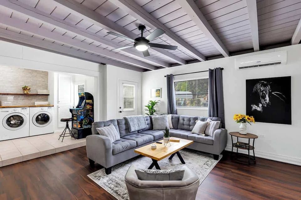 Living room with large sectional couch, 65" HDTV (Netflix & Amazon Prime), ceiling fan, handmade coffee table and stylishly decorated. Laundry room in background, full size Marvel 2 Player Arcade (3 Games: Marvel Super Heroes, X-Men, The Punisher).