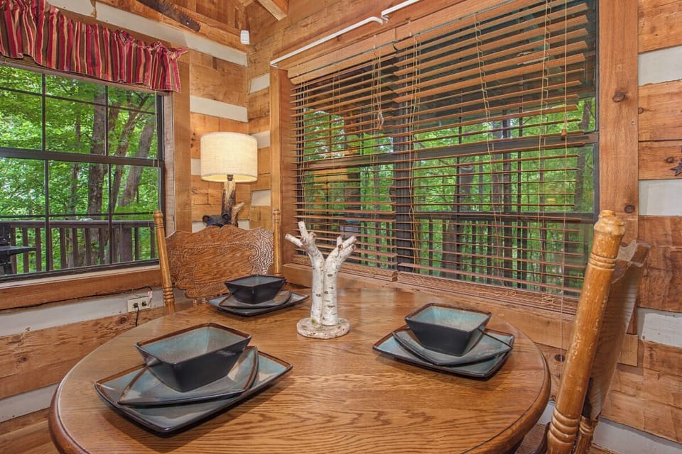 Gather around your private dining table surrounded by warm wood walls and beautiful forest views peeking through every window—your perfect spot for sharing meals together.