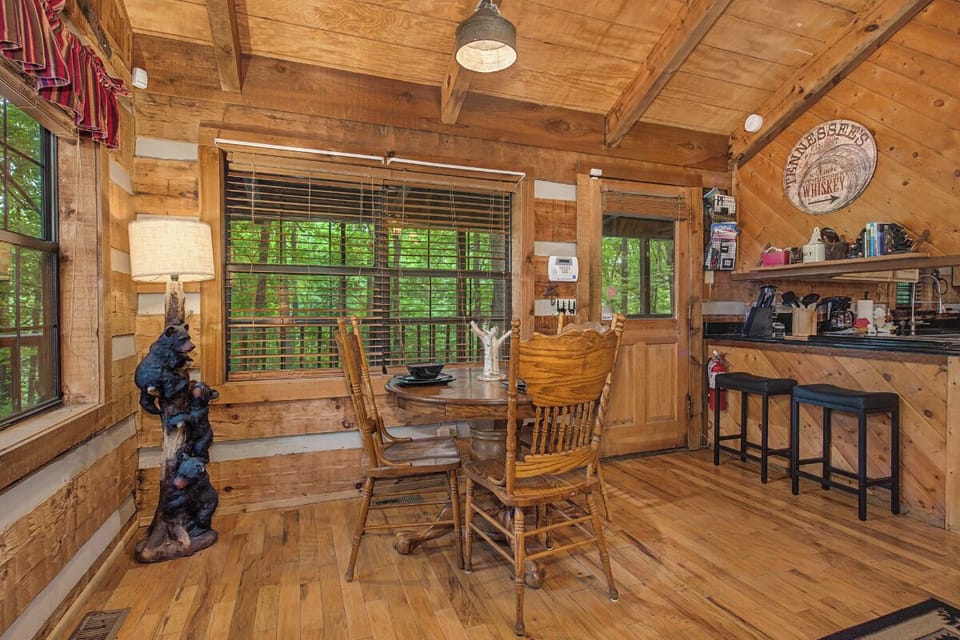 Step into your rustic cabin retreat with warm wood-paneled walls, a cozy dining nook surrounded by forest views, and a welcoming kitchenready for your mountain mornings.