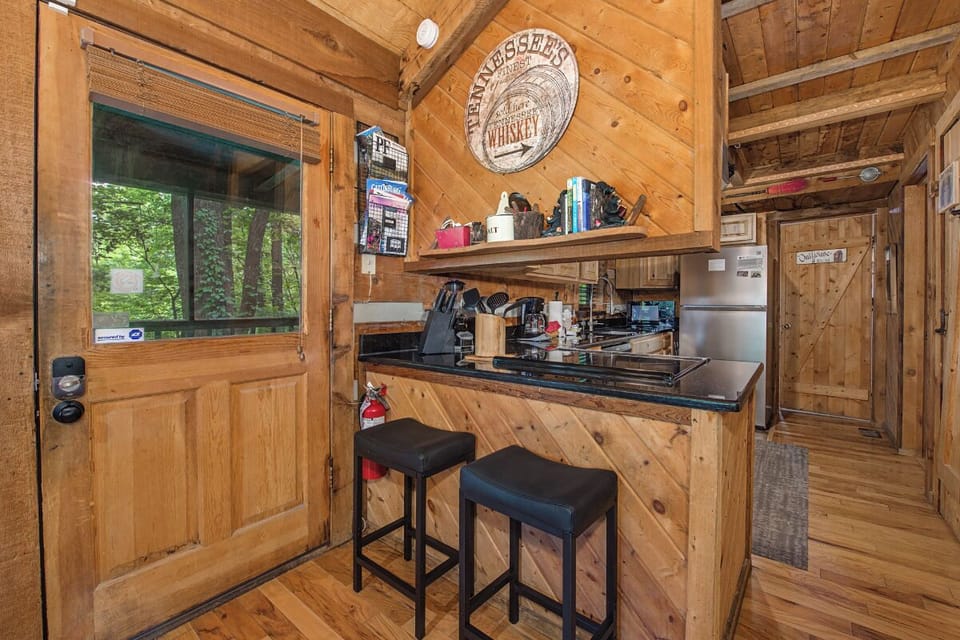 Your rustic cabin kitchen features rich wood walls, a cozy breakfast bar, and all the essentials for preparing meals during your mountain getaway.