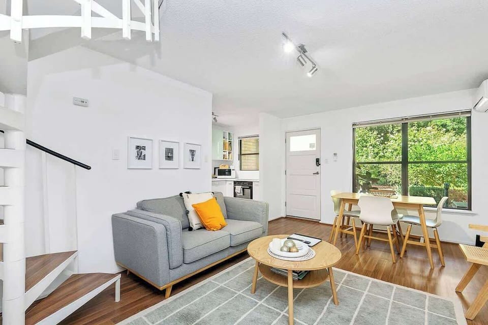 Relax and connect in the open-plan living and dining area, featuring a comfortable sofa, stylish rug, convenient coffee table, and a dining table with seating for four.