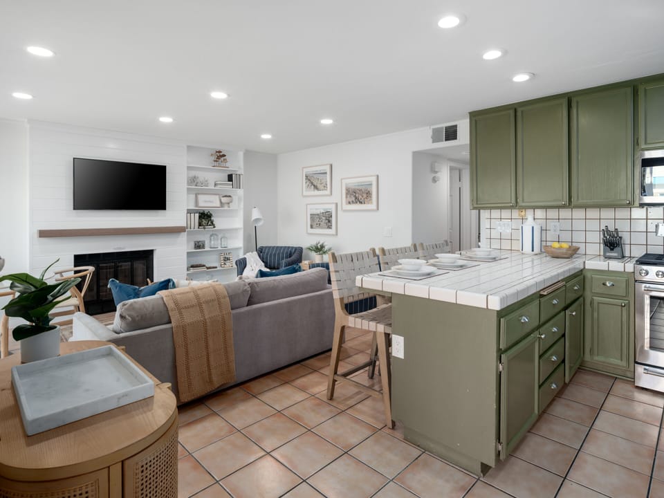 This modern open-plan kitchen with a bar and casual seating features sleek countertops and contemporary cabinetry.