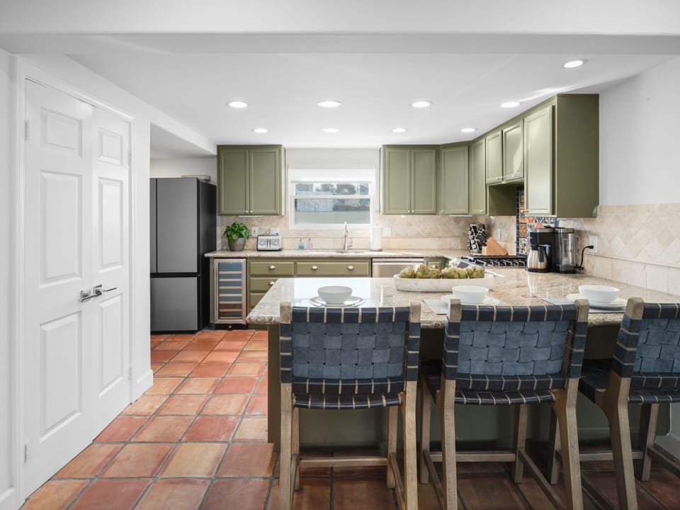 Fully equipped modern kitchen with sleek countertops, ample cabinetry, luxury appliances, and a complete set of utensils.
