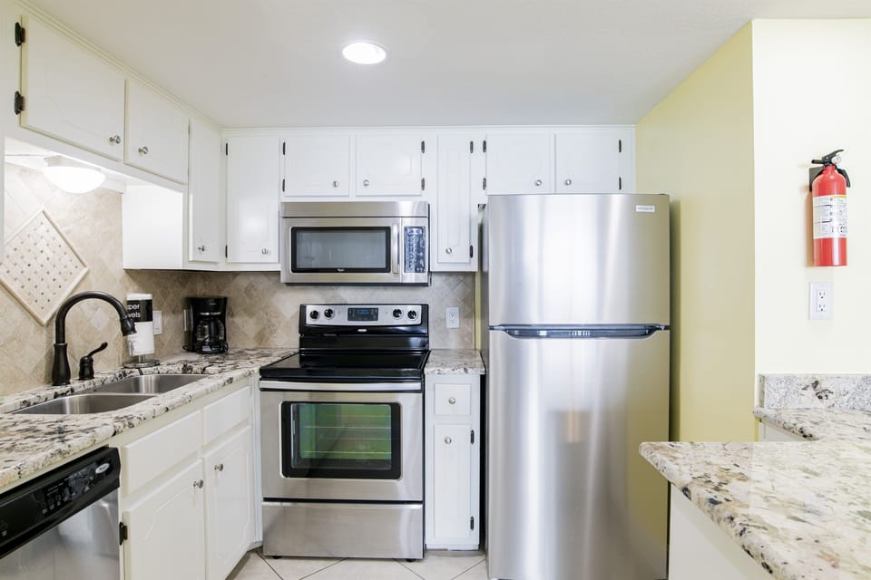 Kitchen With Stainless Steel Appliances, Coffee Maker, Blender, Mixer, Toaster And Plenty Of Pots, Pans And Dishes And Tiled Backsplash