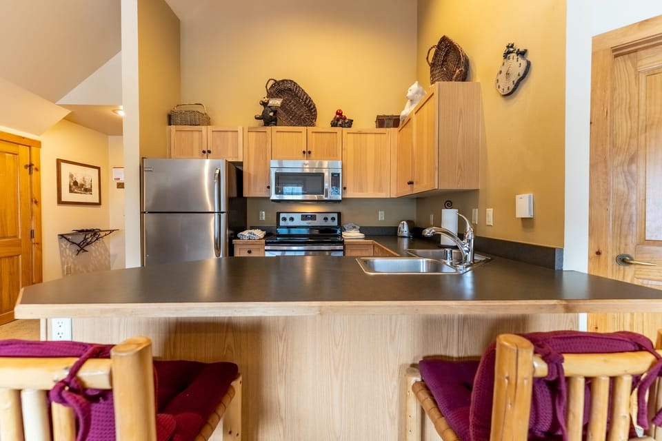 Your fully equipped kitchen features modern appliances and a breakfast bar where you can start each morning with coffee and mountain views.