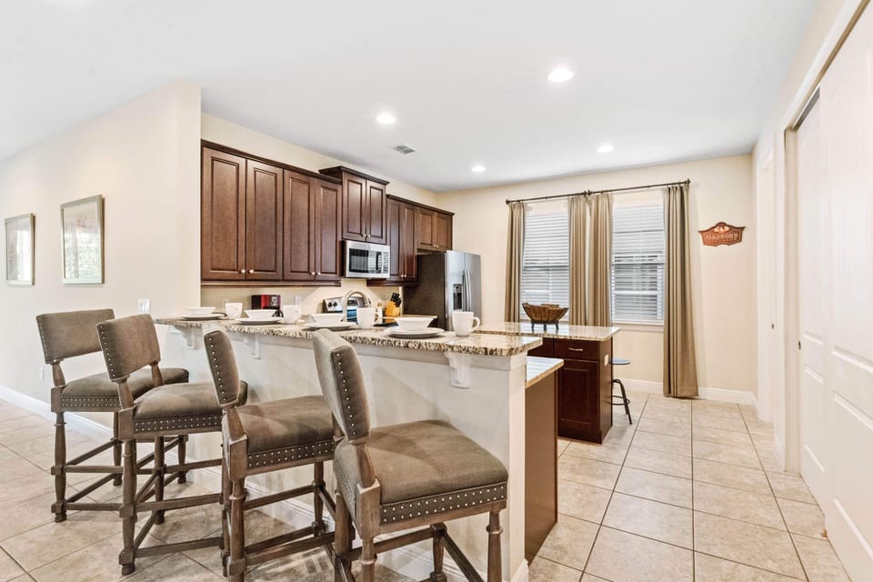 Stunning Kitchen of the Home in Kissimmee Florida - Breakfast Bar with Stylish High Chairs - Elegant and coordinated color palette for a cohesive look - Functional island for additional workspace