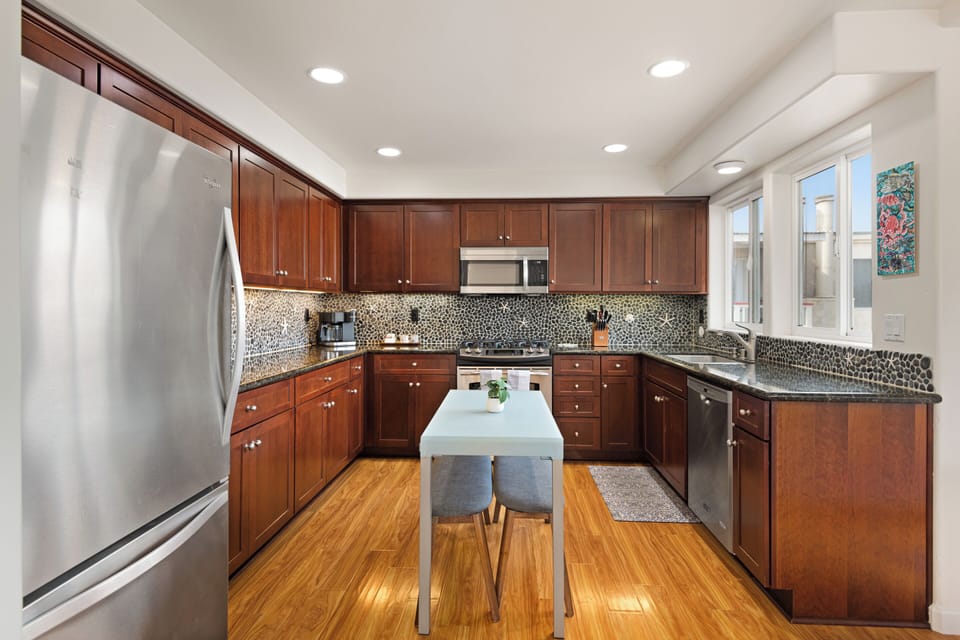 Modern kitchen equipped with stainless steel appliances, quartz countertops, and kitchen island or dining table