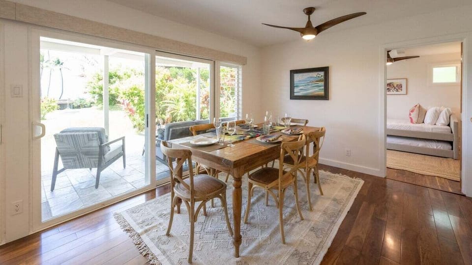 Enjoy meals in a bright dining area featuring a rustic wooden table, six chairs, and sliding doors that open to a lush garden patio.