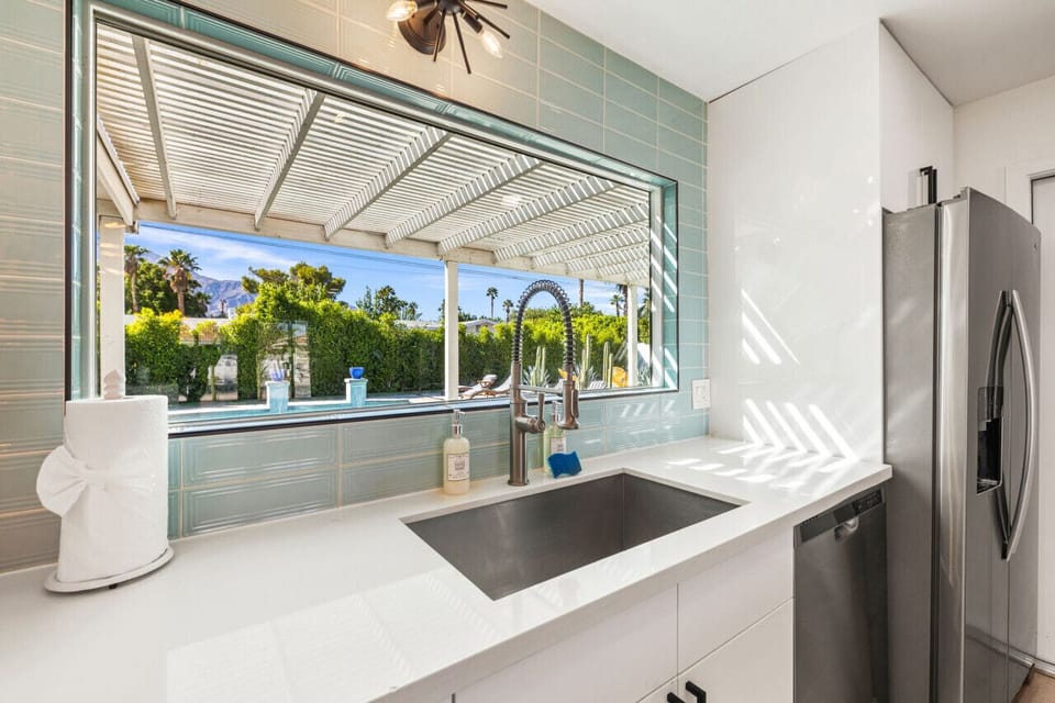 Sunlit kitchen sink w/ a large picture window, sleek counters, and easy views to the covered patio just outside.