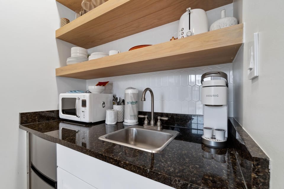 The kitchenette is equipped with granite countertops, a Keurig coffee maker, toaster, microwave, and bar refrigerator.