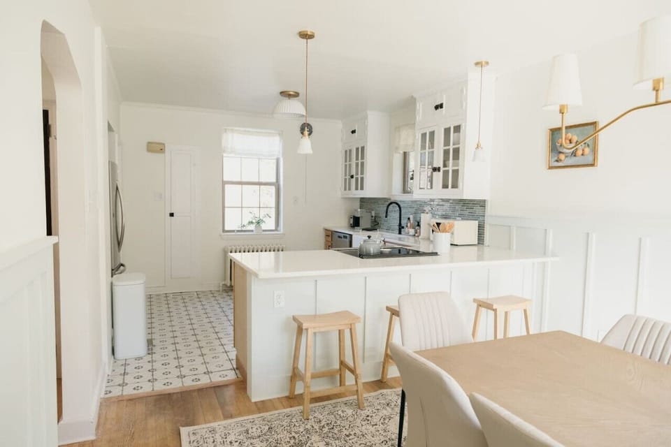 Bright kitchen and dining area with white cabinetry, island, and light wood accents