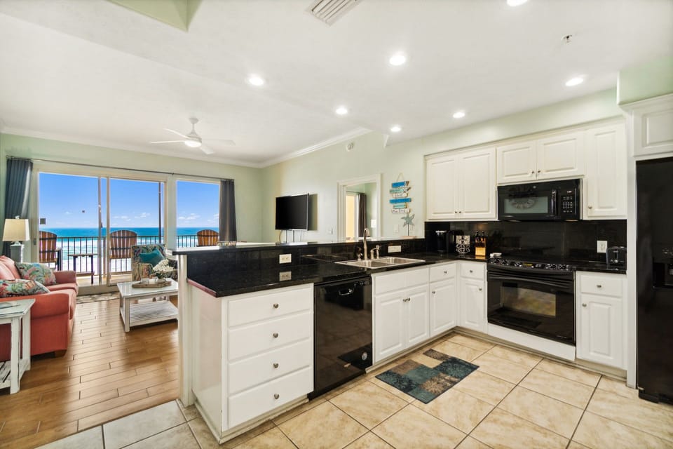 Sleek kitchen w/ dark countertops, ample cabinetry & ocean views to cook with a view.