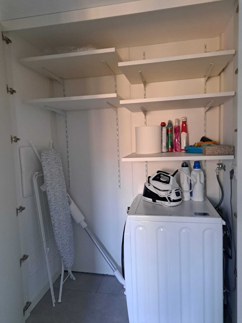 Large storage with washer/dryer combo machine, iron and cleaning products 