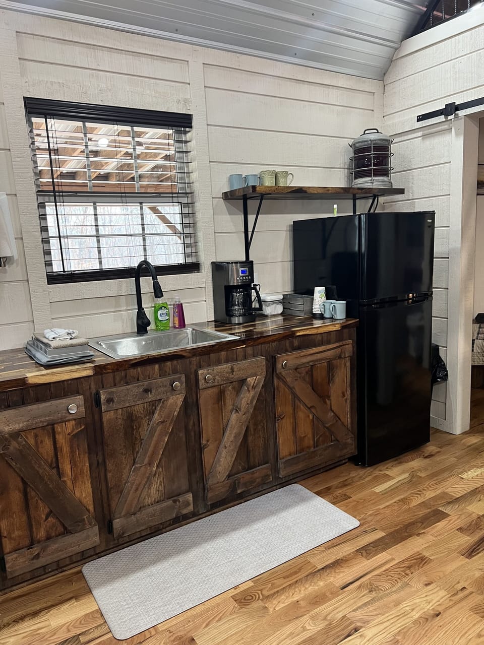 Kitchenette with custom built cabinets, microwave, sink and refrigerator. 