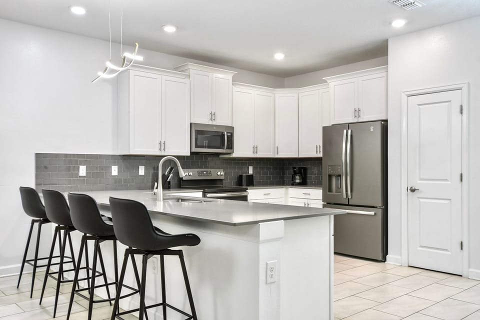 Sleek modern kitchen with stainless steel appliances, stylish bar seating, and elegance.