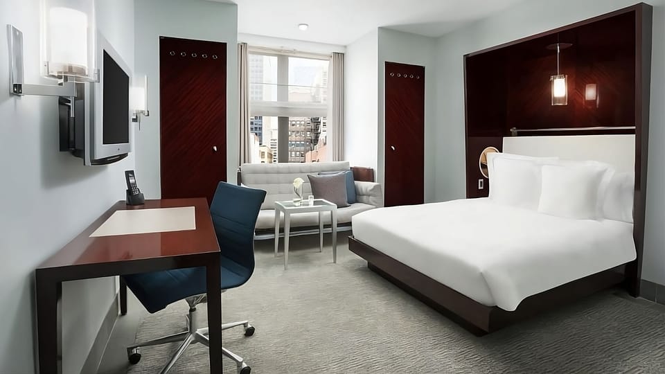 Unwind in crisp linens with a bright workspace and skyline views.
