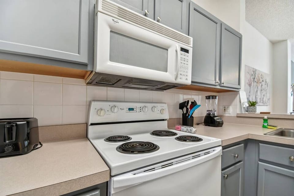 This modern kitchen boasts sleek gray cabinetry and light countertops, creating a clean and functional space. With bright natural light and updated appliances, it’s ideal for preparing meals and enjoying time with guests.