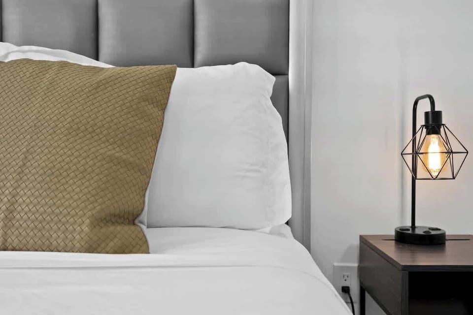 Cozy nights await—modern lighting and plush pillows create a warm, inviting vibe in this minimalist bedroom. Ideal for couples or solo travelers.