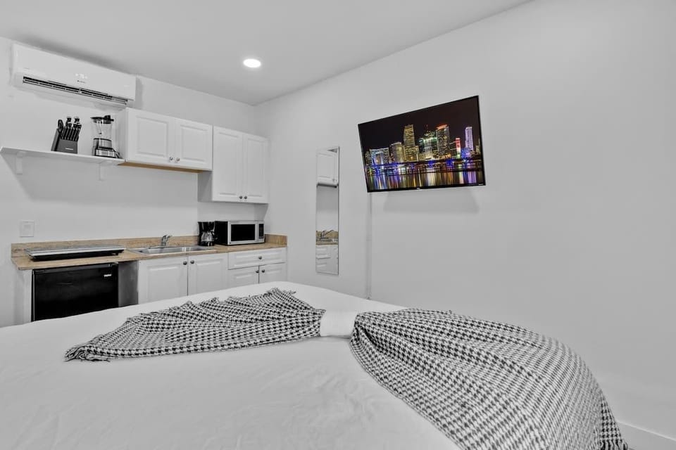 Minimalist studio with comfy bed, kitchenette, and entertainment setup—perfect for beach lovers and city explorers.