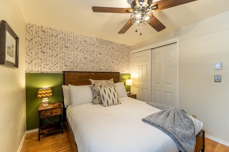 Your cozy bedroom features stylish botanical wallpaper, warm lighting, and comfortable bedding for peaceful nights.