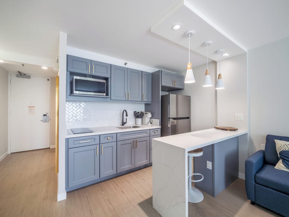 Full Kitchen with microwave, stovetop, and refrigerator - Full kitchen with dining area, refrigerator, microwave, cooktop, garbage disposal, Kureg Coffee maker, basic cookware, dishes, and utensils