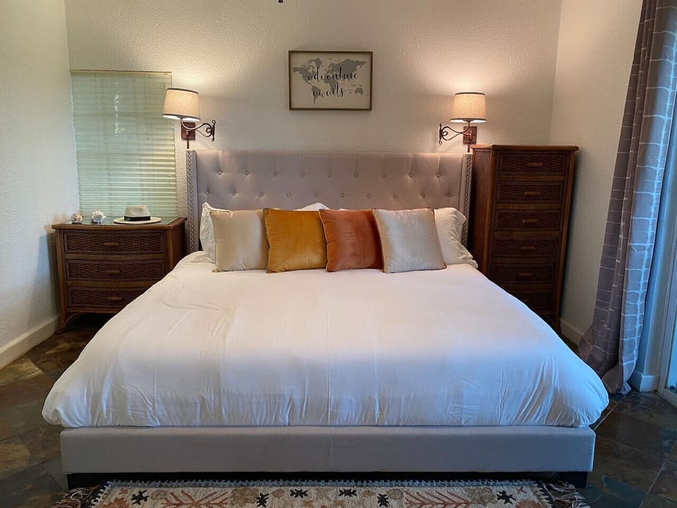 A richly furnished king bedroom with dark wood accents and layered warm lighting throughout