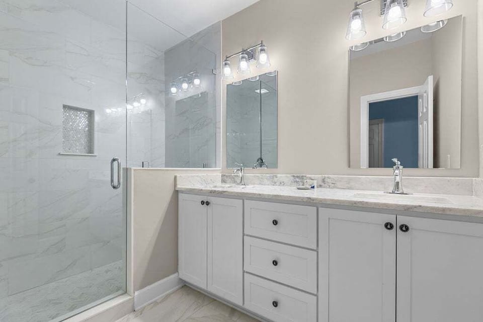 A primary bath has double sinks and a huge walk-in shower