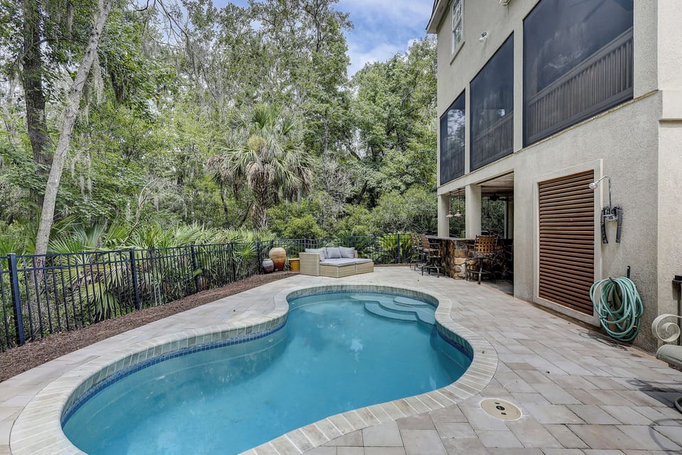 Private pool with outdoor seating, bar with 5 barstools, a gas grill, and a outdoor shower.
