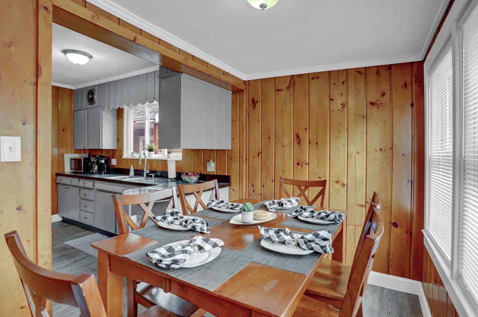 Rustic dining area with wooden walls, modern kitchen, and cozy setup.