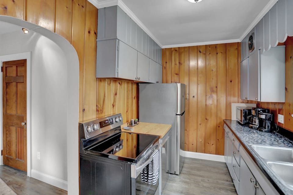Modern kitchen with stainless steel appliances, wooden paneling, and cozy vibe.