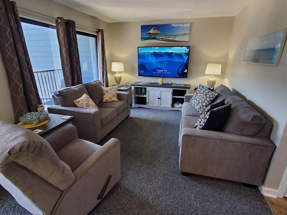 Living room with 65" Smart LED TV. Double patio doors and pull out queen sofa.