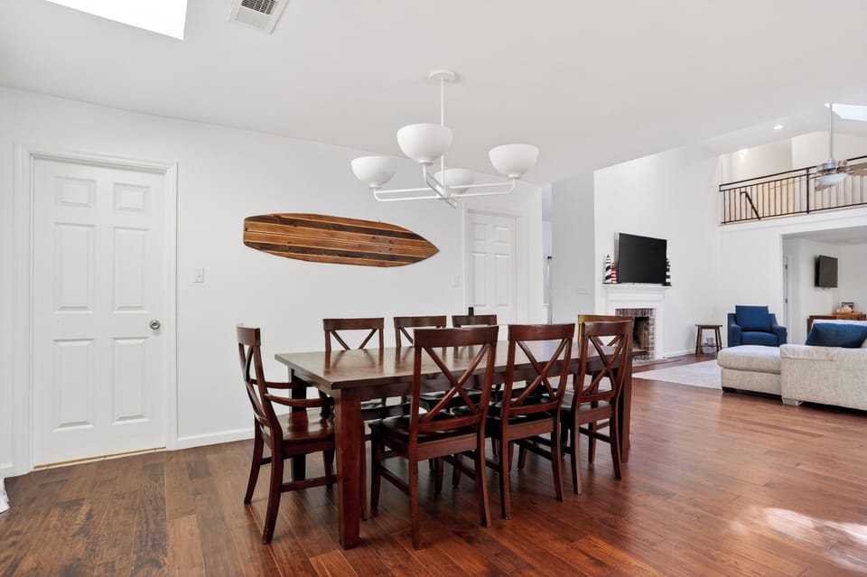 Bright open dining space with a wooden table, coastal accents, and a seamless flow into the airy living room.